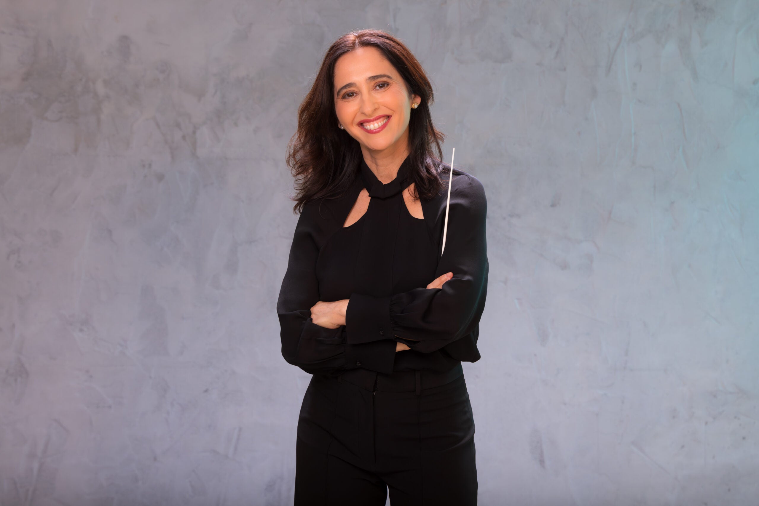 Rakefet Hak holding a baton wearing a black shirt and black pants.
