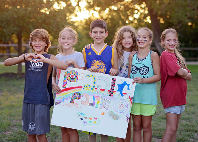 Campers at Camp Young Judaea Texas hold a Hebrew sign that translates as 'We love you.' (Courtesy of authors)
