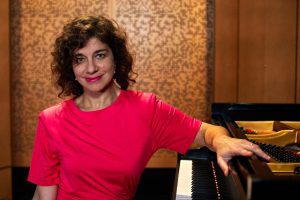 A woman sits at a piano