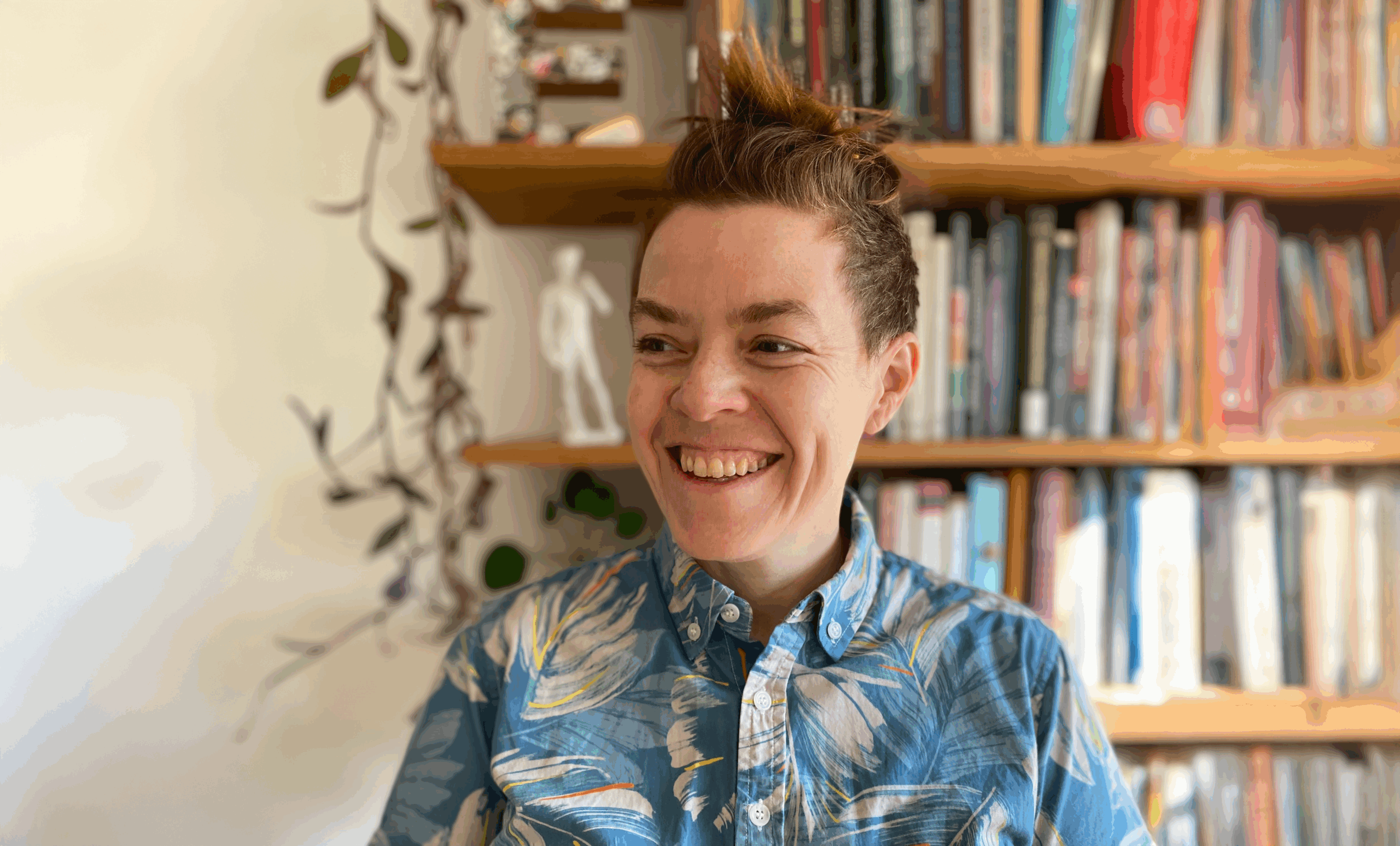 headshot of Wilbourne smiling, with a bookshelf in the background
