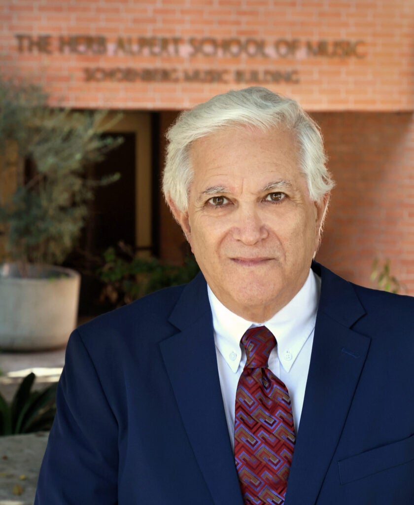 Photo of man in blue jacket and red tie in front of The UCLA Herb Alpert School of Music