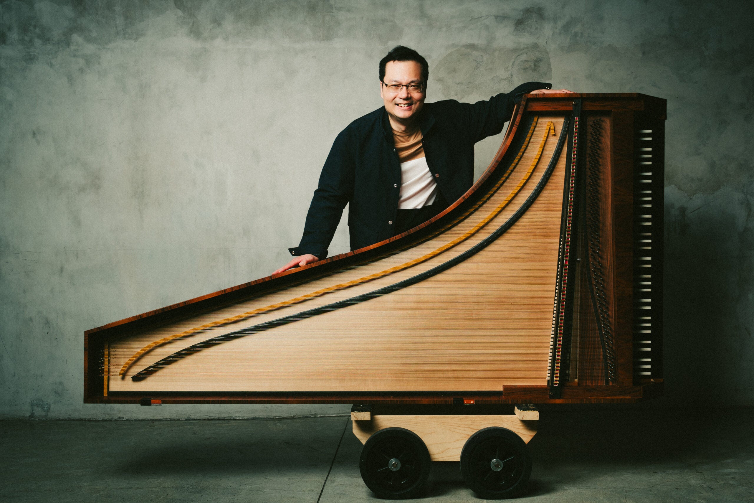 Man standing with 18th century fortepiano on its side.