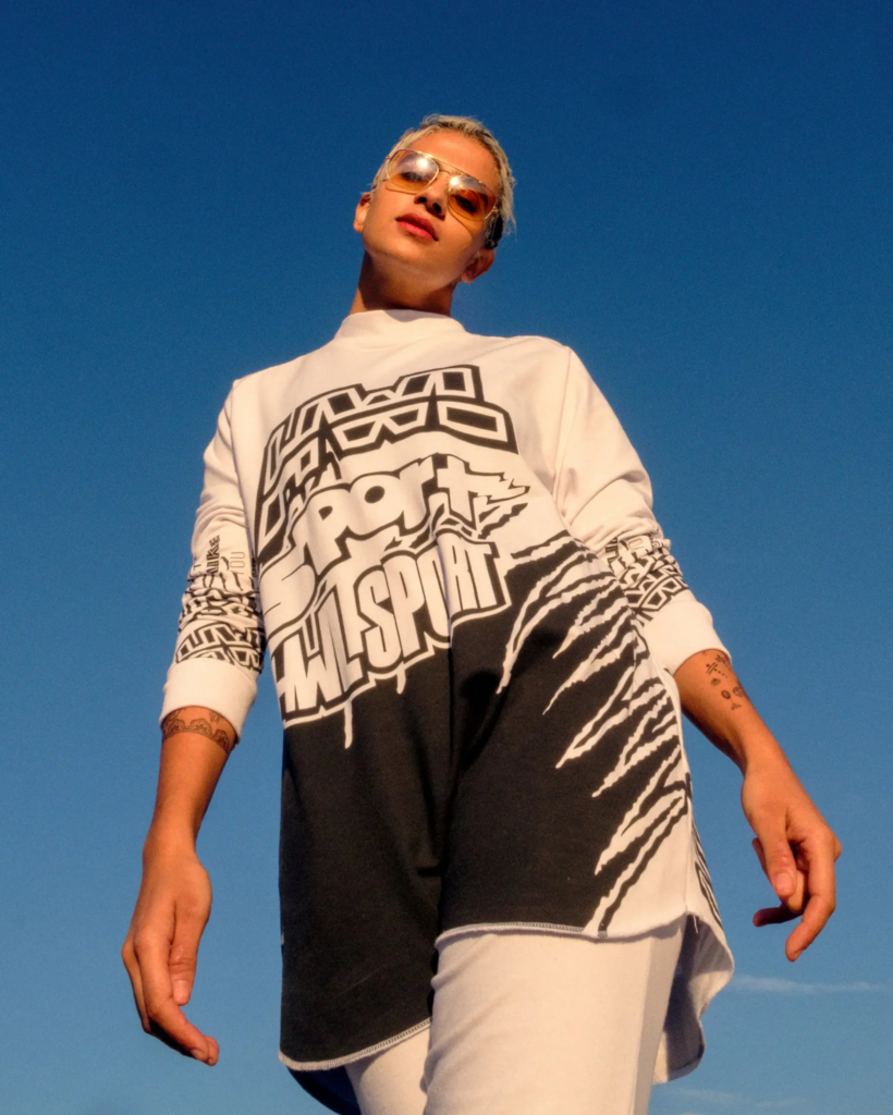 Woman in white t shirt and sunglasses walking toward the camera.