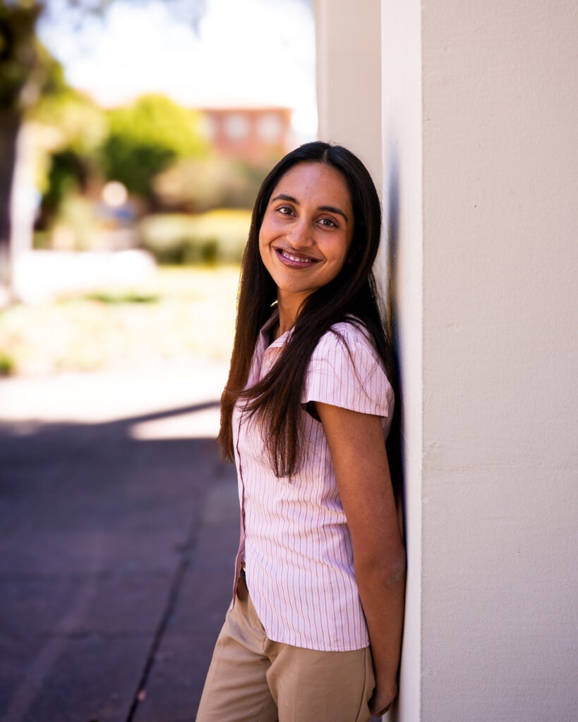 woman standing in pink shirt against a pillar.