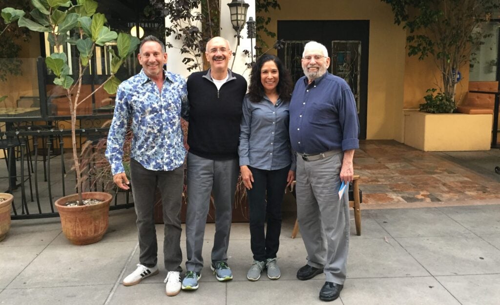 Three men and one woman smiling in a photograph.