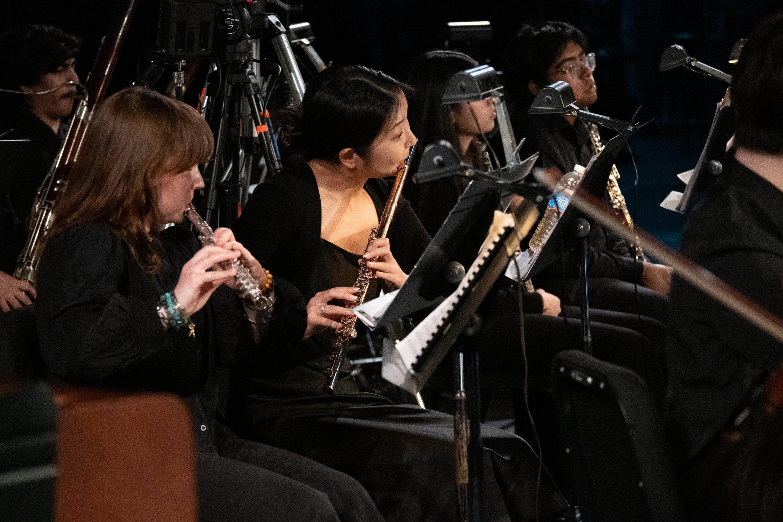 Two flute players playing in an orchestra.
