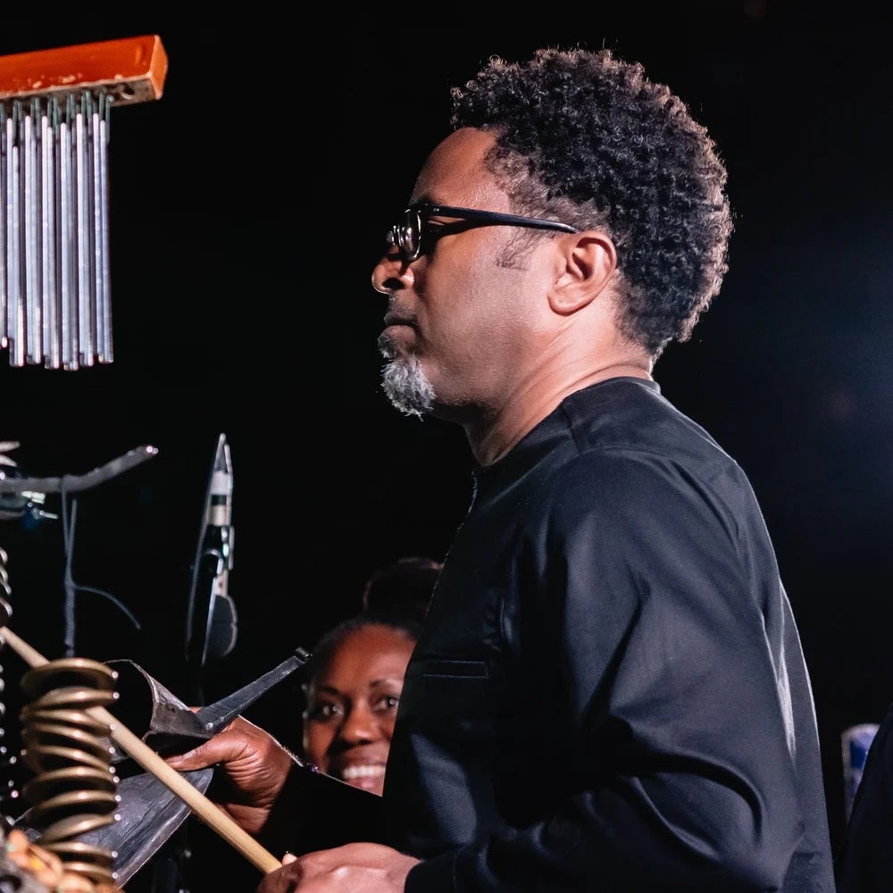 Man wearing a black shirt playing percussion on stage.