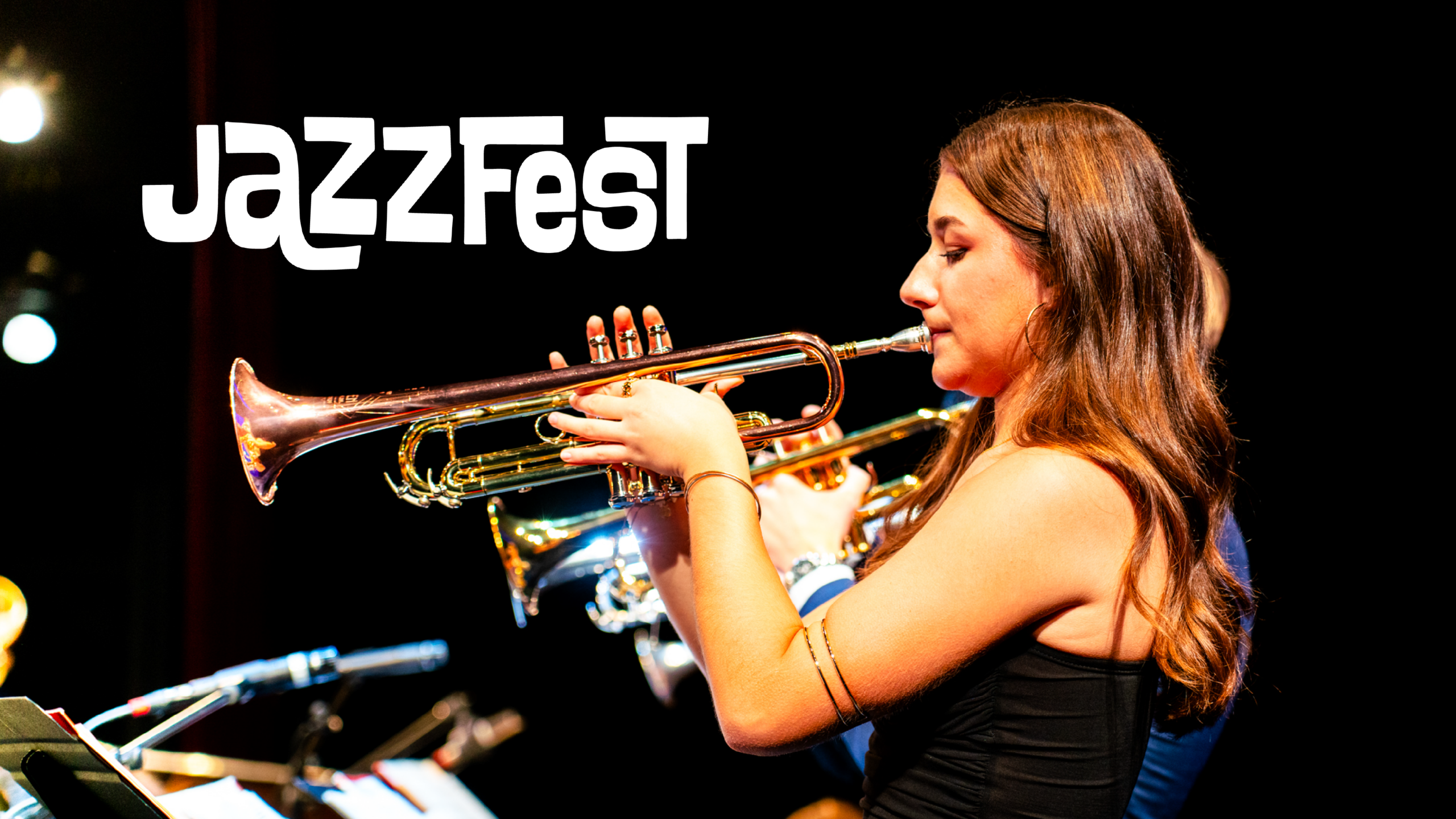 Woman in black dress playing trumpet on a bandstand. The graphic reads "Jazzfest"