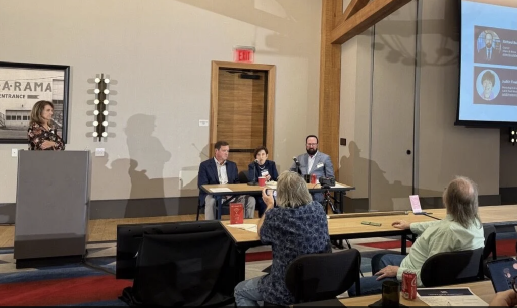 Three people at a desk answering questions from a crowd during a panel.