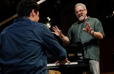 Faculty Member instructing a student playing the piano.